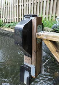 feeder mounted to 2x4 over koi pond